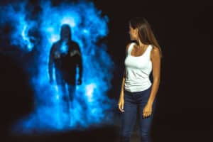 A woman standing in front of a blue smoke projection at home.