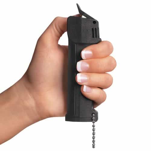 A woman's hand holding a Mace® Triple Action Police Pepper Spray on a chain.