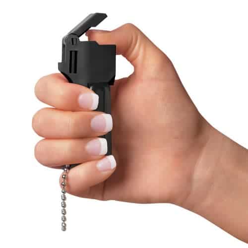 A hand holding a Mace® Pocket Model Triple Action fire extinguisher with a chain.