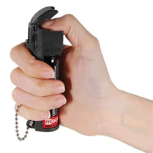 A hand holding a Mace® PepperGard Personal Pepper Spray.