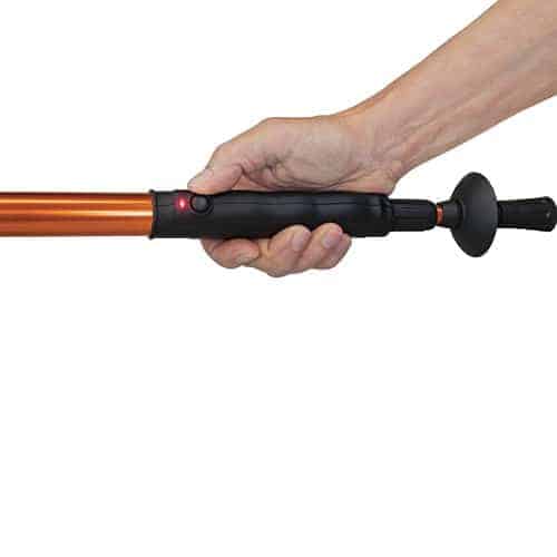 A person wielding a walking stick with an orange handle, equipped with the powerful Hike 'n Strike 950,000 Volts Stun Walking Cane.