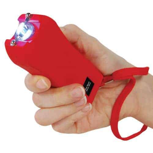 A hand holding a Runt Rechargeable Stun Gun With Flashlight And Wrist Strap Disable Pin.