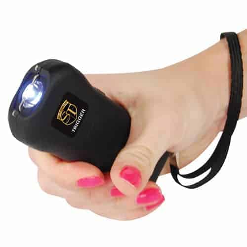 A woman gripping a Trigger Stun Gun Flashlight with Disable Pin tightly in her hand, ready to illuminate her surroundings.