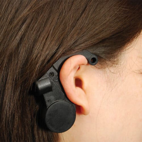 A woman's ear with a black button on it.