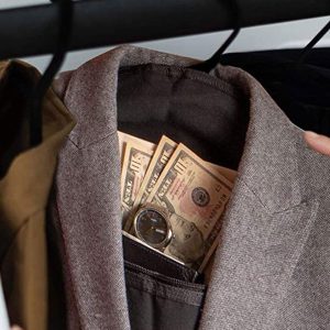 A man is discreetly slipping money into a Hanger Diversion Safe hidden pocket on his jacket.