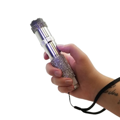 A hand holds the RhineStun 75,000,000* Stun Flashlight, a metallic flashlight adorned with rhinestones and a wrist strap, blending style and security.