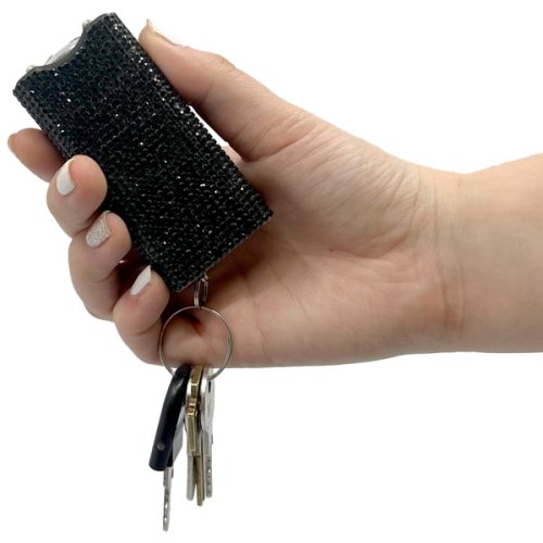 A hand holds a Rhinestun Keychain Stun Gun with a black, textured finish and several keys attached, combining security with style.