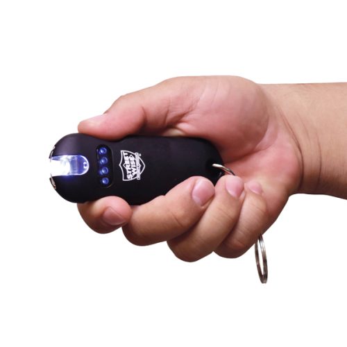 A hand holds a sleek black SMART 24,000,000* Keychain Stun Gun with a keychain attachment, featuring a glowing LED at the front and bright blue side indicator lights.