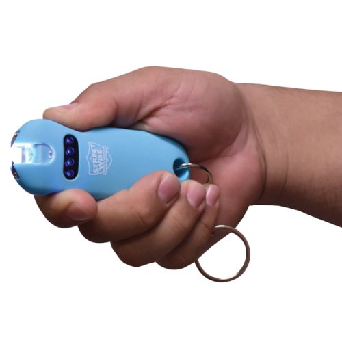 A person holds a SMART 24,000,000* Keychain Stun Gun in blue with an activated flashlight and attached key ring for convenience.