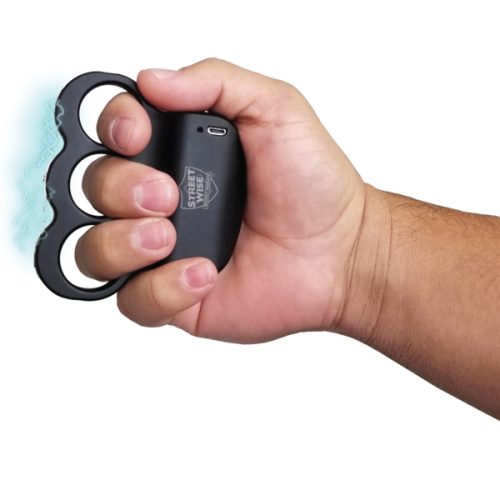 A hand holds the sleek TRIPLE Sting Ring 28,000,000 Stun Gun, styled like brass knuckles, with electric blue sparks crackling from the front.